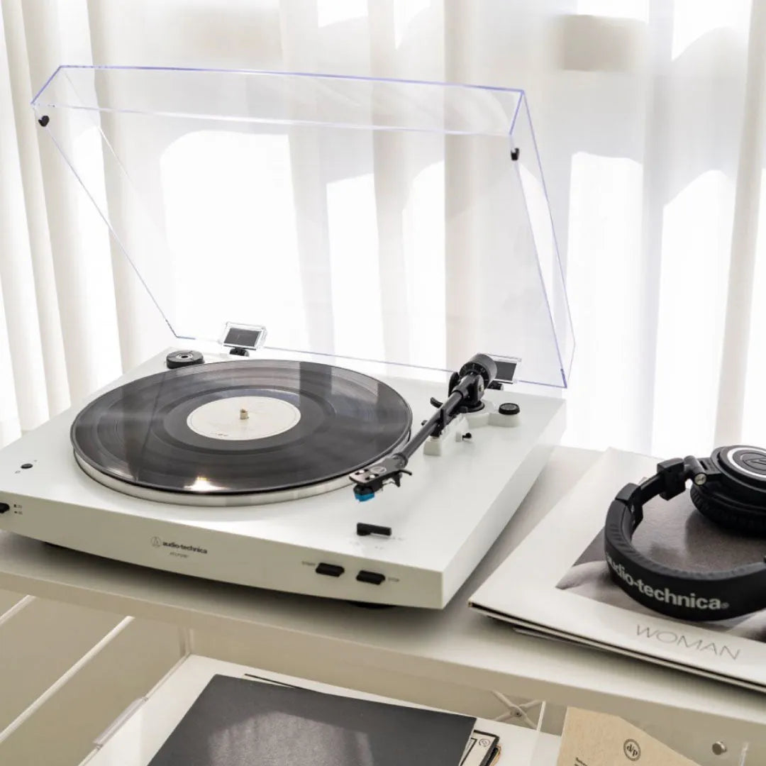 Audio-Technica AT-LP3XBT, automatinis patefonas su Bluetooth 5.2 - ausinės ant knygos su logotipu